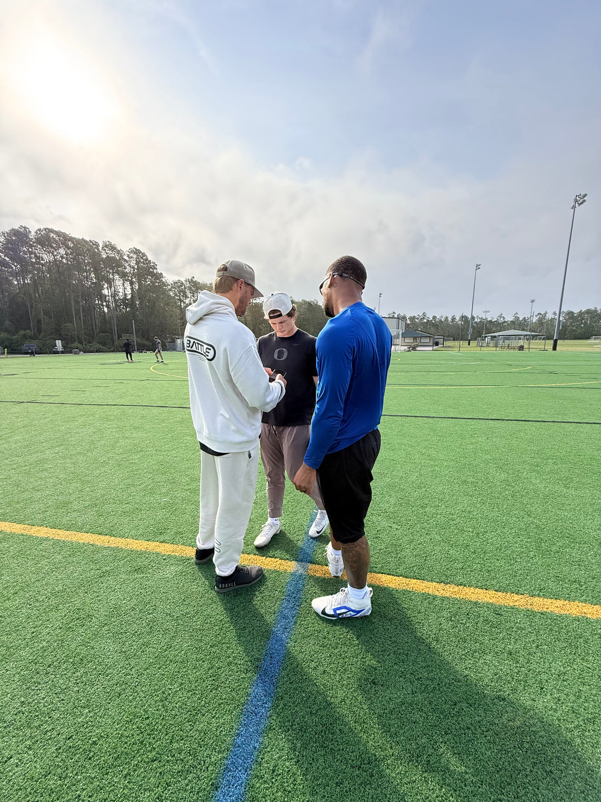 Kinetex coaches reviewing throwing film with a quarterback on the field